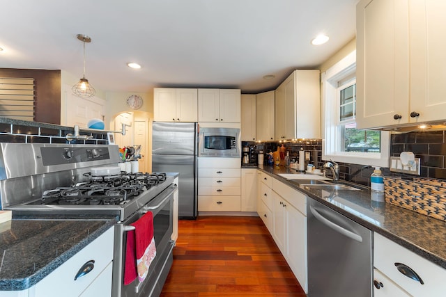 736 Webster St, Lewiston, ME 04240 - kitchen with stainless steel appliances, dark wood-type flooring, backsplash, hanging light fixtures, and white cabinets