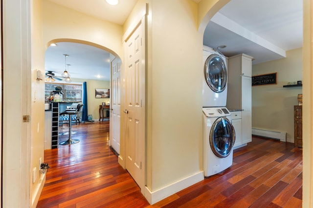 736 Webster St, Lewiston, ME 04240 - washroom featuring stacked washer and clothes dryer, baseboard heating, arched walkways, and dark wood finished floors