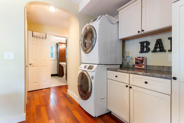 736 Webster St, Lewiston, ME 04240 - laundry area with stacked washer and clothes dryer, cabinet space, arched walkways, and hardwood / wood-style floors