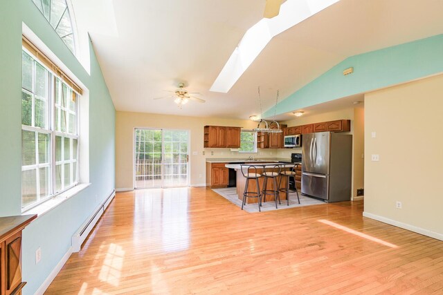 421 Cushing Rd, Cushing, ME 04563 - kitchen featuring stainless steel appliances, lofted ceiling, a baseboard heating unit, brown cabinets, and a skylight
