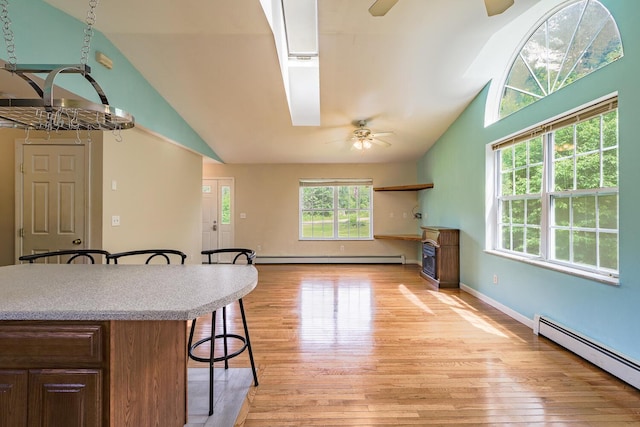 421 Cushing Rd, Cushing, ME 04563 - kitchen featuring a ceiling fan, a baseboard radiator, lofted ceiling, a breakfast bar, and light wood-type flooring