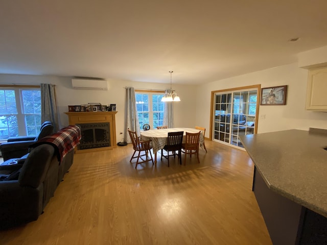 48 Stoney Ridge Rd, Eddington, ME 04428 - dining area with light wood finished floors, a wall unit AC, a chandelier, and a fireplace