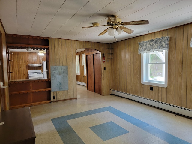 183 Folsom Pond Rd, Lincoln, ME 04457 - empty room featuring tile patterned floors, arched walkways, baseboard heating, ceiling fan, and wood walls