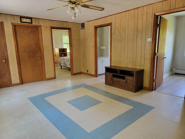 183 Folsom Pond Rd, Lincoln, ME 04457 - unfurnished bedroom with wooden walls, light flooring, connected bathroom, baseboard heating, and a ceiling fan
