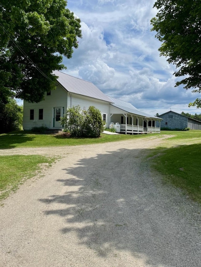 183 Folsom Pond Rd, Lincoln, ME 04457 - view of front facade with driveway, a front yard, a metal roof, and a porch