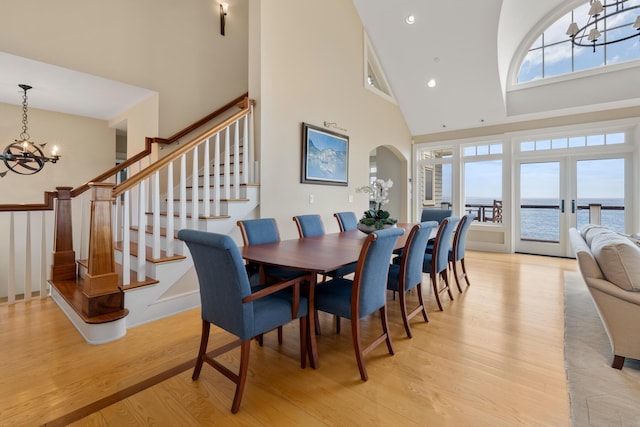 121 Bald Head Cliff Rd, York, ME 03902 - dining space featuring a chandelier, high vaulted ceiling, light wood-style flooring, stairs, and a water view