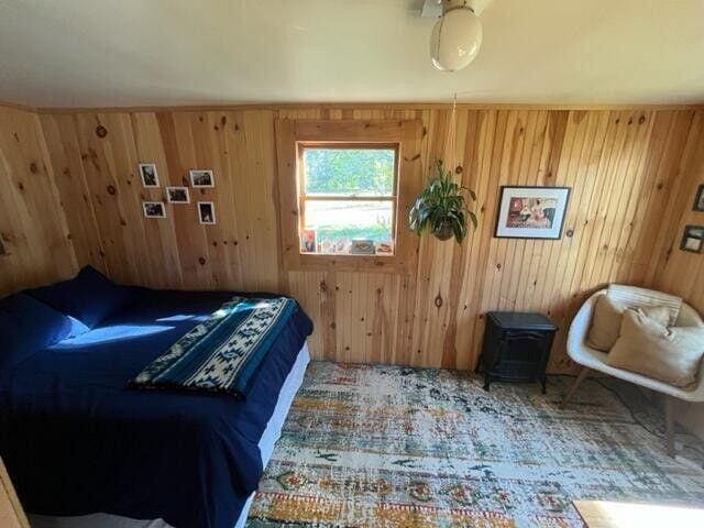 6 Chicken St, Starks, ME 04911 - carpeted bedroom with a wood stove and wooden walls