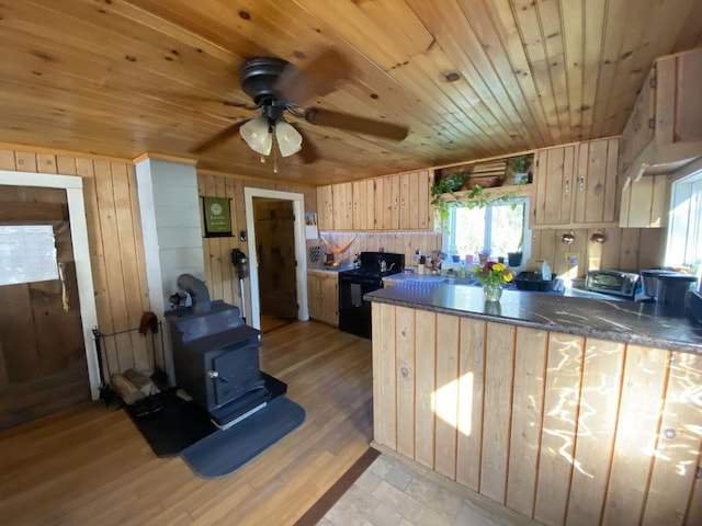 6 Chicken St, Starks, ME 04911 - kitchen with wood walls, a wood stove, light brown cabinets, black range oven, and wooden ceiling