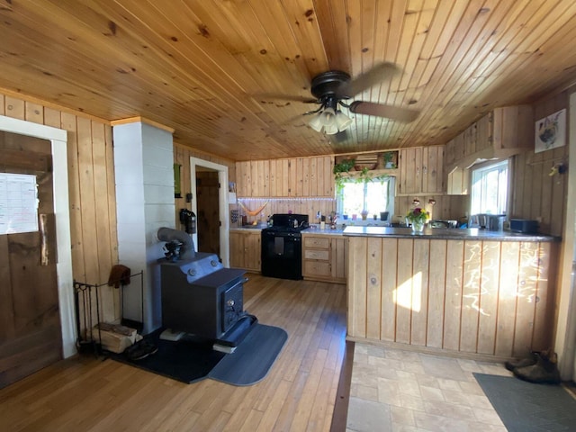 6 Chicken St, Starks, ME 04911 - kitchen with black range, light brown cabinets, a wood stove, wood walls, and ceiling fan