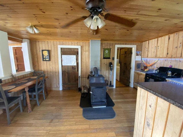 6 Chicken St, Starks, ME 04911 - kitchen with black gas range, a wood stove, wood walls, wood ceiling, and light wood-type flooring