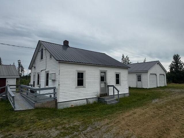 238 Shadagee Rd, Cornville, ME 04976 - back of property with a chimney, a metal roof, a yard, a garage, and an outbuilding