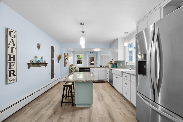97 Forest Ave, Orono, ME 04473 - kitchen with appliances with stainless steel finishes, a baseboard heating unit, light wood-style floors, a kitchen bar, and white cabinets