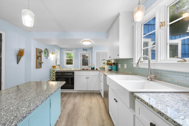 97 Forest Ave, Orono, ME 04473 - kitchen with black oven, light wood-style flooring, backsplash, white cabinets, and light stone countertops