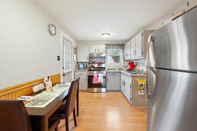 119 Falvey St, Bangor, ME 04401 - kitchen with stainless steel appliances, under cabinet range hood, light wood finished floors, light countertops, and backsplash