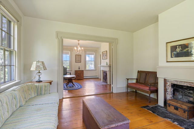 426 Meadow Rd, Topsham, ME 04086 - living room featuring a fireplace, hardwood / wood-style floors, a chandelier, and a baseboard radiator