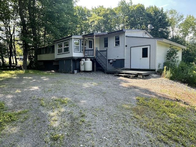 182 Dover Rd, Charleston, ME 04422 - view of front of home with a sunroom, view of scattered trees, and driveway