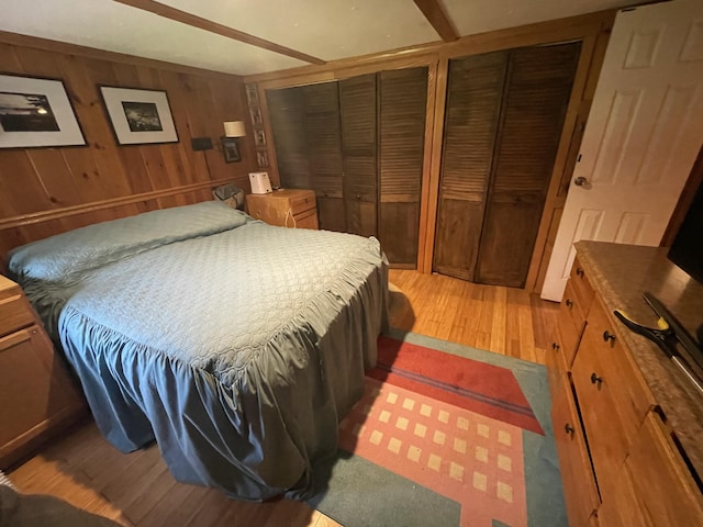 182 Dover Rd, Charleston, ME 04422 - bedroom with light wood-style flooring, multiple closets, and wood walls