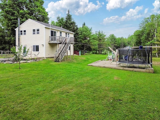71 Morgan Rd, Burnham, ME 04922 - view of green lawn featuring stairway, a trampoline, a wooden deck, and view of wooded area