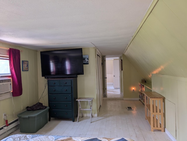 419 Common Rd, Union, ME 04862 - bedroom featuring a textured ceiling, light wood-style flooring, a baseboard heating unit, cooling unit, and vaulted ceiling
