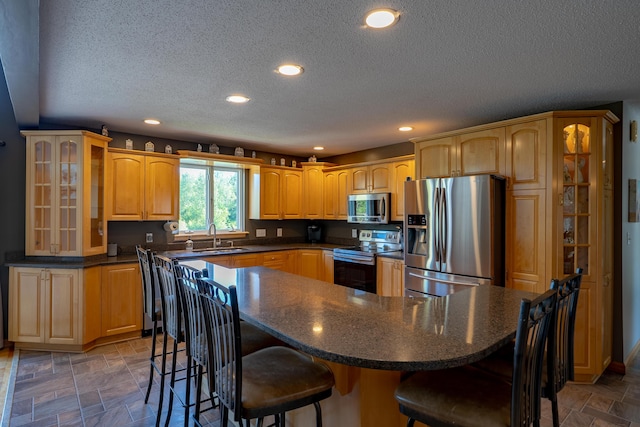 78 Lakeview Rd, Glenburn, ME 04401 - kitchen featuring stainless steel appliances, dark countertops, a kitchen breakfast bar, a textured ceiling, and glass insert cabinets