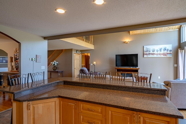 78 Lakeview Rd, Glenburn, ME 04401 - kitchen featuring open floor plan, a textured ceiling, arched walkways, dark stone countertops, and recessed lighting
