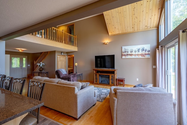 78 Lakeview Rd, Glenburn, ME 04401 - living area featuring light wood finished floors, stairway, a high ceiling, and a glass covered fireplace