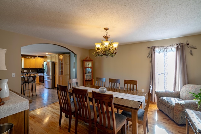 78 Lakeview Rd, Glenburn, ME 04401 - dining area featuring arched walkways, a chandelier, a textured ceiling, and light wood-style floors
