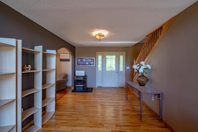 78 Lakeview Rd, Glenburn, ME 04401 - foyer entrance with a wood stove, light wood-style floors, a textured ceiling, arched walkways, and stairway