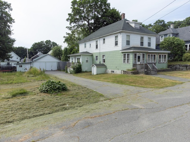 18/20 Beech St, East Millinocket, ME 04430 - view of front of house featuring a chimney, roof with shingles, a detached garage, a front yard, and a storage unit