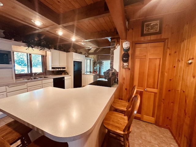 151 Schooland Rd, New Sweden, ME 04762 - kitchen with black appliances, wood walls, a breakfast bar area, light countertops, and white cabinetry