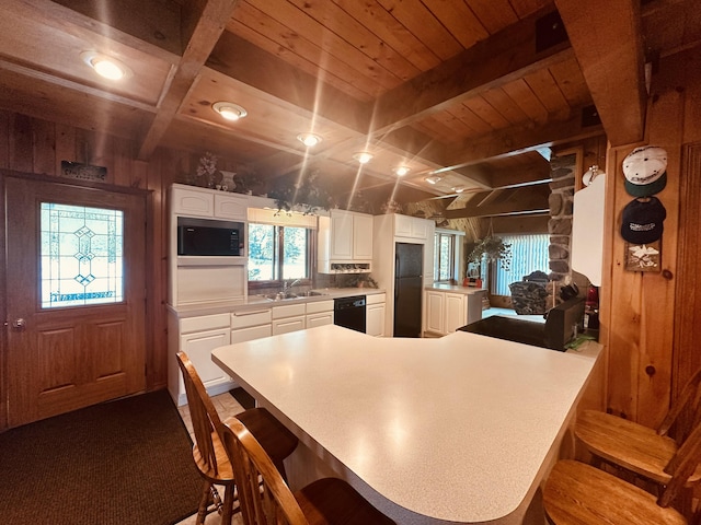 151 Schooland Rd, New Sweden, ME 04762 - kitchen with black appliances, a breakfast bar, white cabinetry, light countertops, and a wooden ceiling with exposed beams