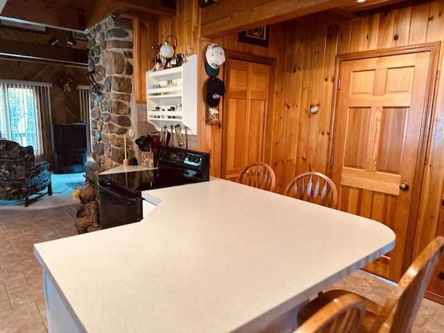 151 Schooland Rd, New Sweden, ME 04762 - kitchen featuring black electric range oven, wooden walls, beamed ceiling, a peninsula, and light stone finish flooring