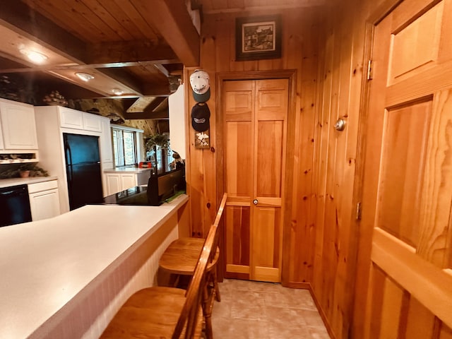 151 Schooland Rd, New Sweden, ME 04762 - kitchen with black appliances, wood walls, white cabinets, a wood ceiling with exposed beams, and light countertops