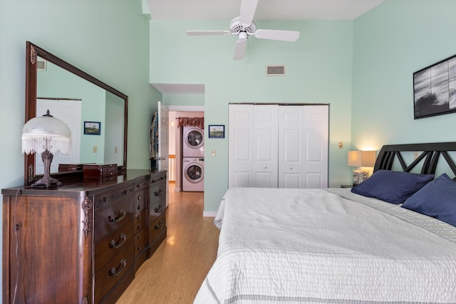 36 Ocean House Way Unit E4, York, ME 03909 - bedroom featuring stacked washing machine and dryer, a towering ceiling, light wood-type flooring, a closet, and a ceiling fan