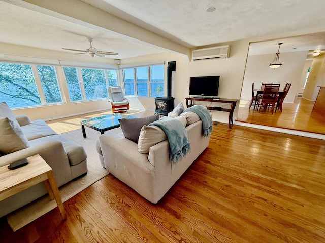 48 Sheltons Rd, Trenton, ME 04605 - living area with a wood stove, a wall mounted AC, wood finished floors, ceiling fan, and beamed ceiling