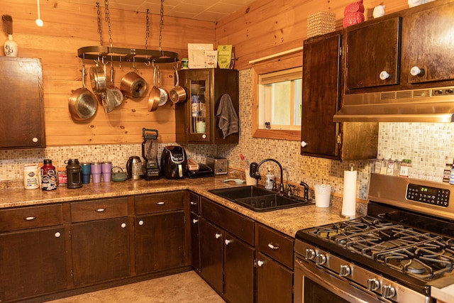 143 Mayfield Rd, Moscow, ME 04920 - kitchen featuring gas stove, under cabinet range hood, backsplash, dark brown cabinetry, and wood walls