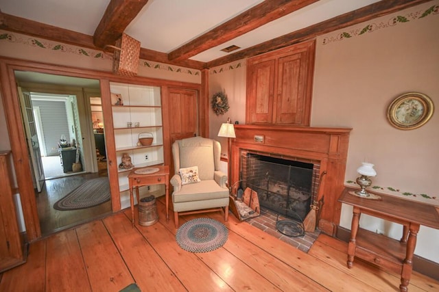 337 Copeland Hill Rd, Holden, ME 04429 - sitting room featuring a brick fireplace, beamed ceiling, and wood-type flooring