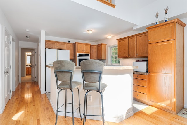 61 Dwelly Point Rd, Franklin, ME 04634 - kitchen featuring oven, freestanding refrigerator, a center island, a breakfast bar area, and light wood-style flooring