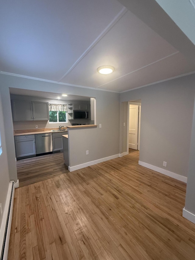 69 Heath St, Oakland, ME 04963 - kitchen with appliances with stainless steel finishes, baseboard heating, light wood finished floors, gray cabinets, and ornamental molding