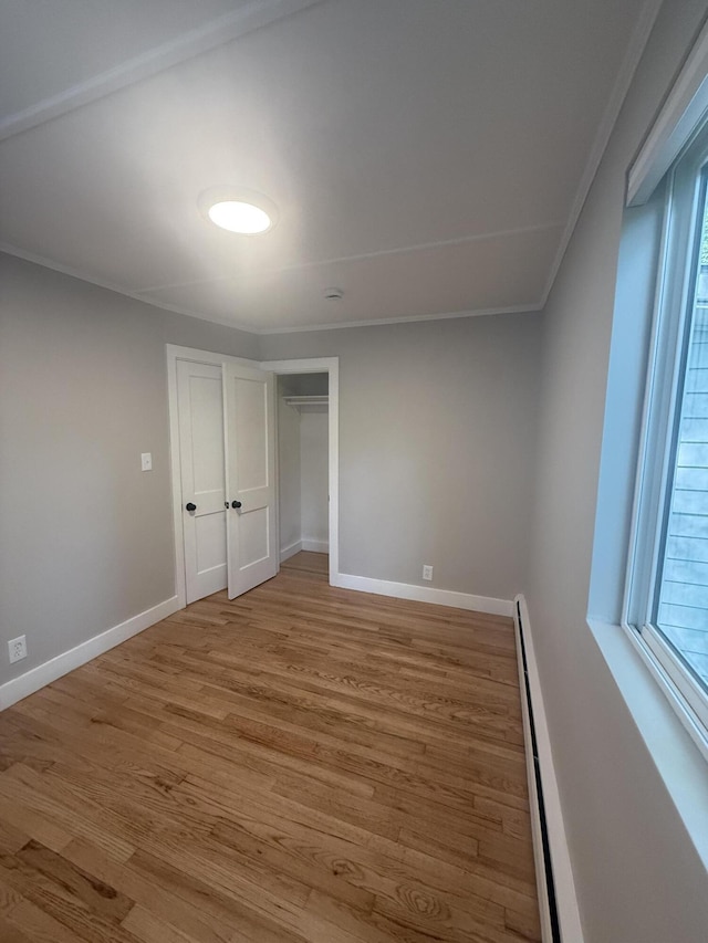69 Heath St, Oakland, ME 04963 - unfurnished bedroom featuring baseboard heating, wood finished floors, ornamental molding, and a closet