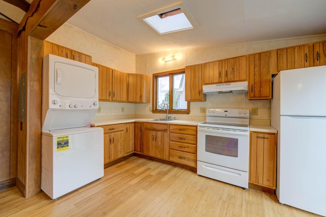 61 Shore Rd, Sebago, ME 04029 - kitchen with white appliances, under cabinet range hood, estacked washer and dryer, light countertops, and light wood-type flooring