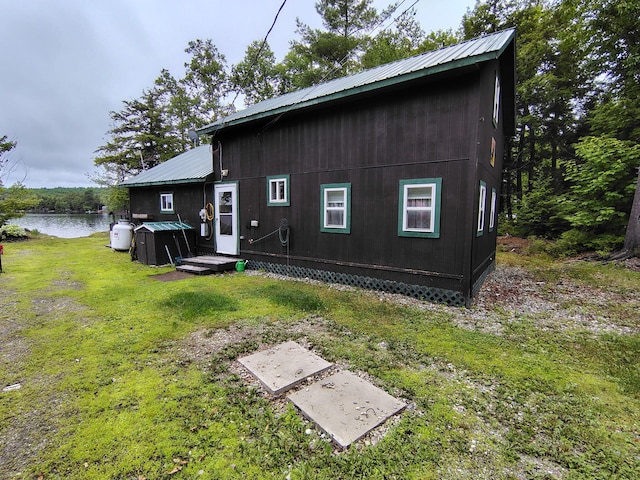 114 E Shore Rd, Benedicta Twp, ME 04733 - back of property with a metal roof, a lawn, and a water view