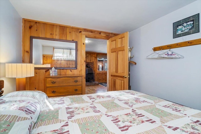 48 Green Bay Rd, Newfield, ME 04095 - bedroom with wood walls, a wood stove, and wood finished floors