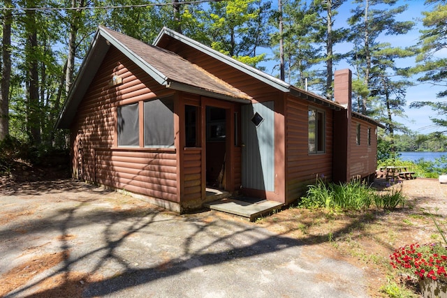 48 Green Bay Rd, Newfield, ME 04095 - view of front of home with faux log siding, a chimney, and a water view
