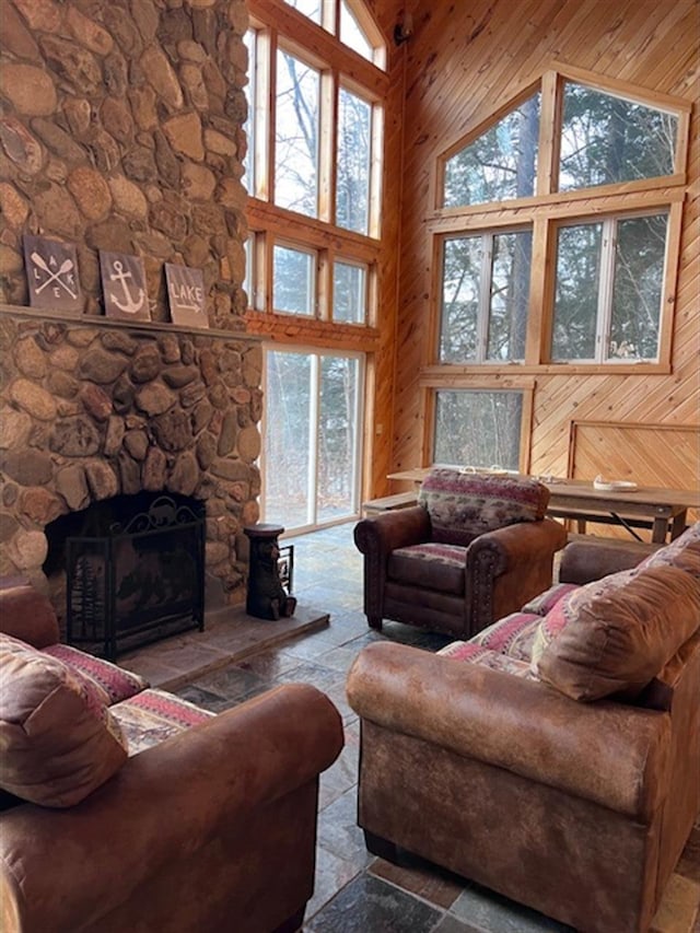 24 Cliffside Dr, Saint Albans, ME 04971 - living room featuring wooden walls, high vaulted ceiling, a stone fireplace, and stone tile floors