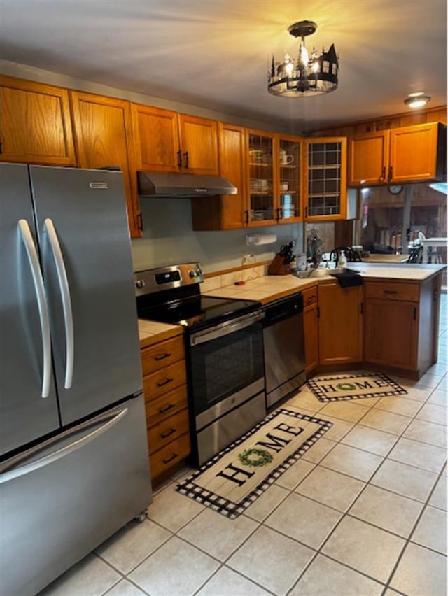 24 Cliffside Dr, Saint Albans, ME 04971 - kitchen featuring appliances with stainless steel finishes, under cabinet range hood, light tile patterned floors, a chandelier, and brown cabinetry