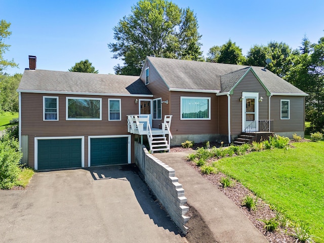 63 N Shore Dr, Owls Head, ME 04854 - view of front facade with a garage, asphalt driveway, a chimney, roof with shingles, and a front lawn