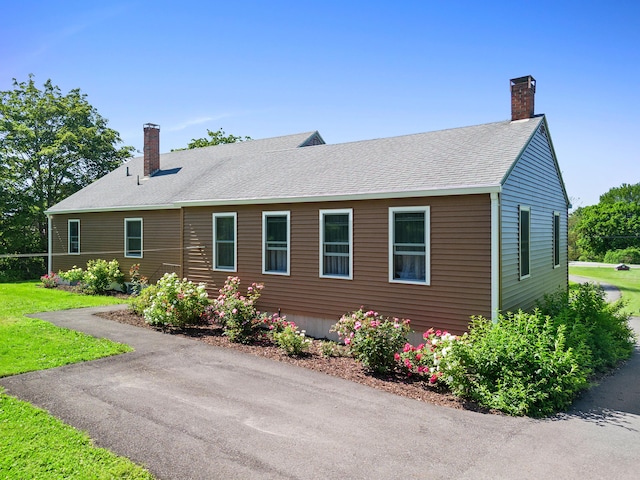 63 N Shore Dr, Owls Head, ME 04854 - view of side of home with a chimney, a shingled roof, and a lawn