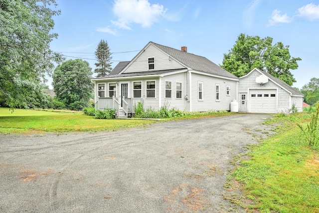 23 W St, Benton, ME 04901 - view of front of property featuring a chimney, a detached garage, asphalt driveway, an outbuilding, and a front lawn