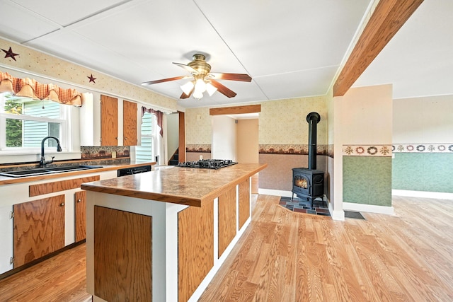 23 W St, Benton, ME 04901 - kitchen featuring wallpapered walls, light wood finished floors, wainscoting, a wood stove, and black appliances